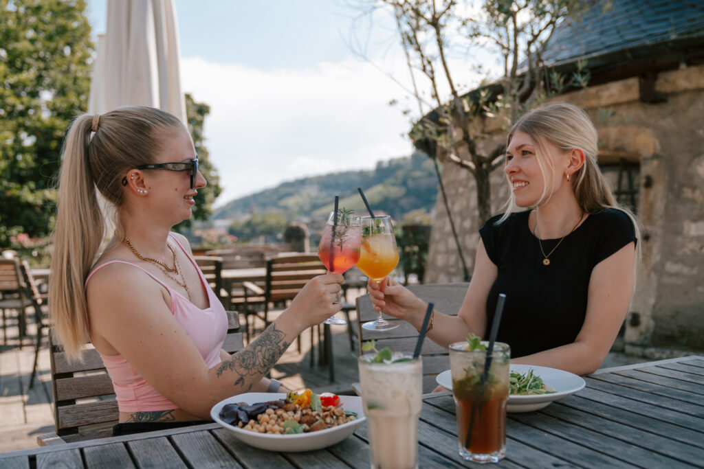 Zwei junge Mädels beim anstoßen auf der Terrasse von Locanda in Würzburg